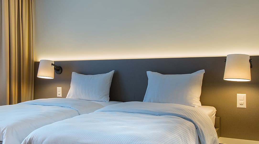 A modern double room in the b_smart Motel Landquart with two beds, wall lamps, and soft lighting
