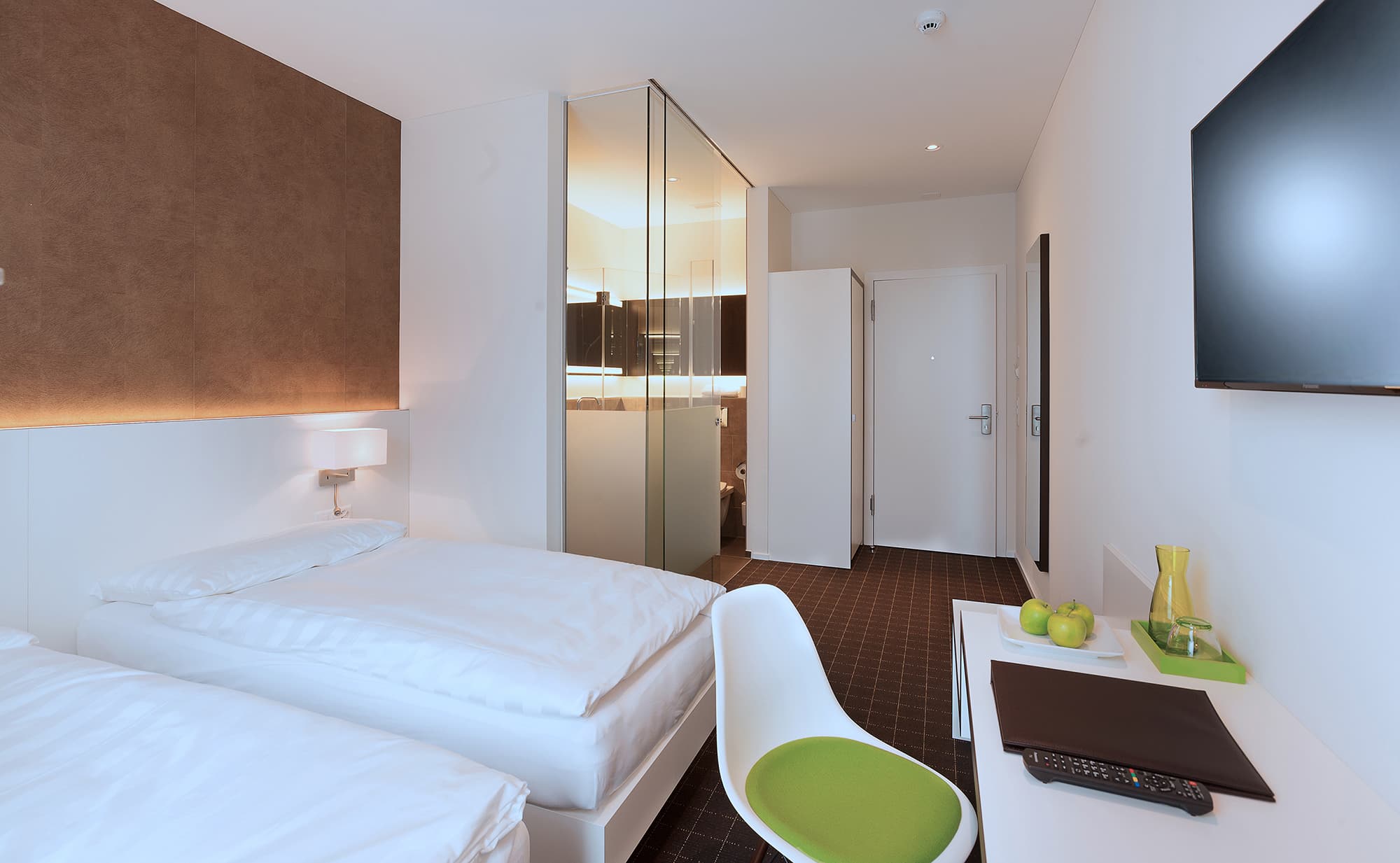 Two twin beds in a modern standard double room at the b smart motel in Basel with a small desk a chair and a flat-screen TV