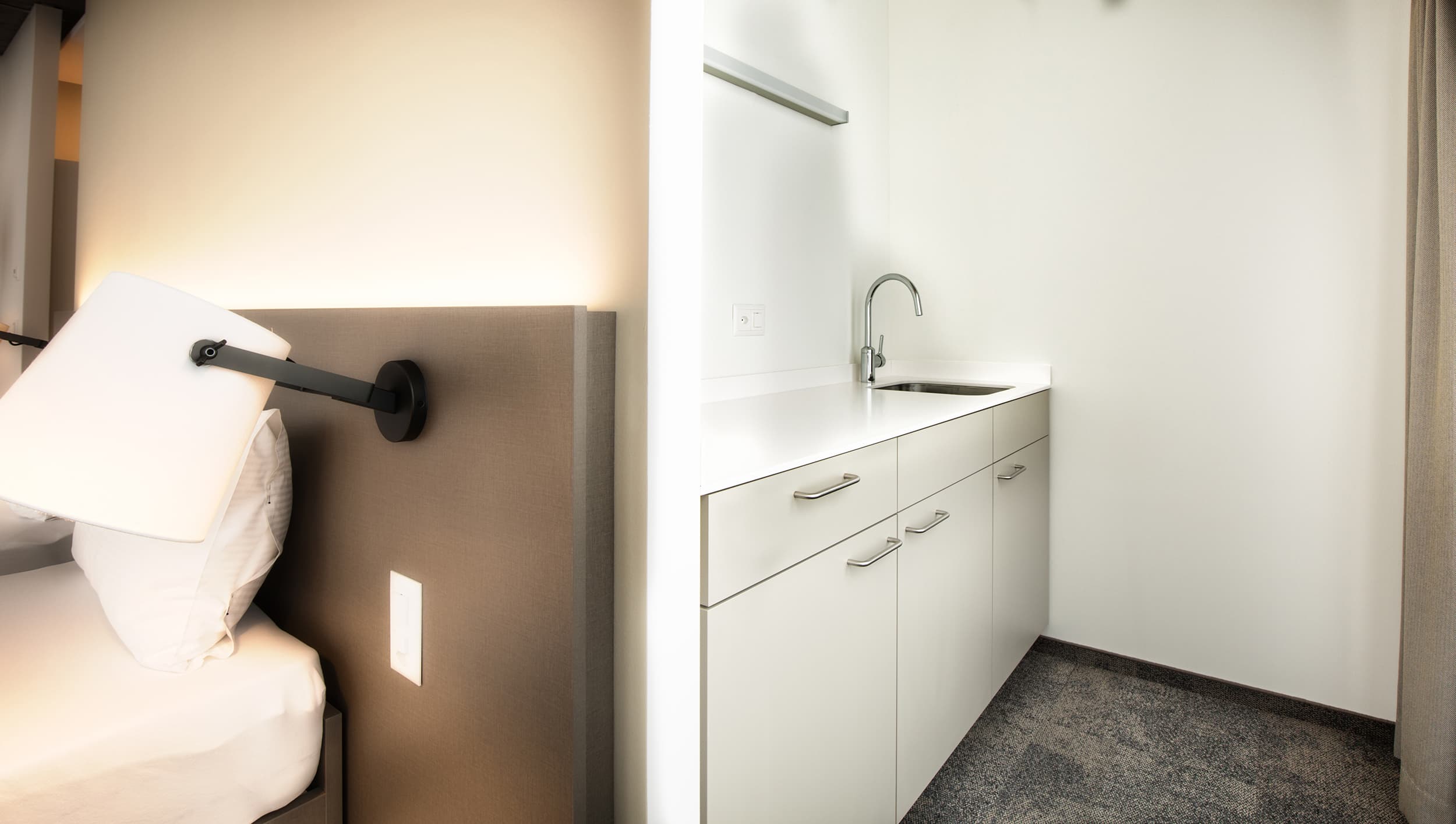 A modern hotel room in the Junior Suite at B_Smart Motel Landquart with a bed and a built-in kitchen